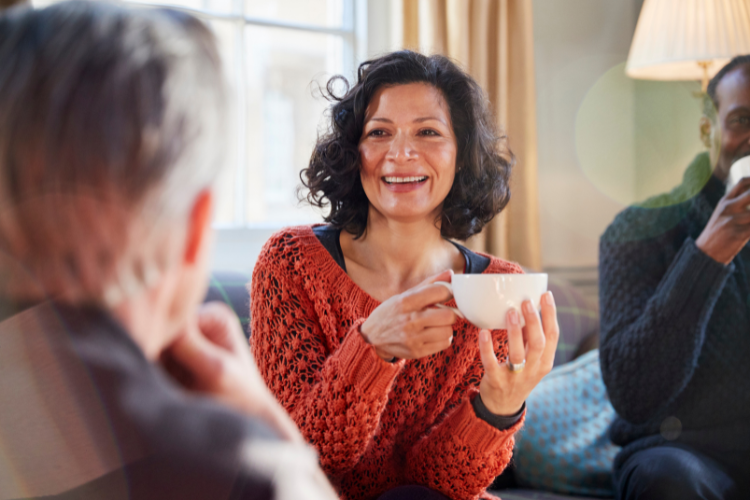 Woman drinking a cup of coffee and talking with a group of people